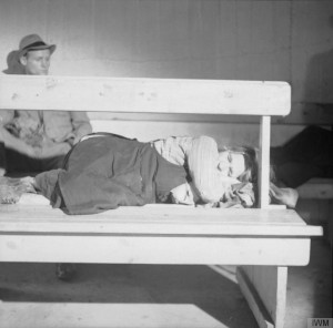 A homeless German woman sleeping on a bench in one of Hamburg's large public air raid shelters. © IWM (BU 10918)